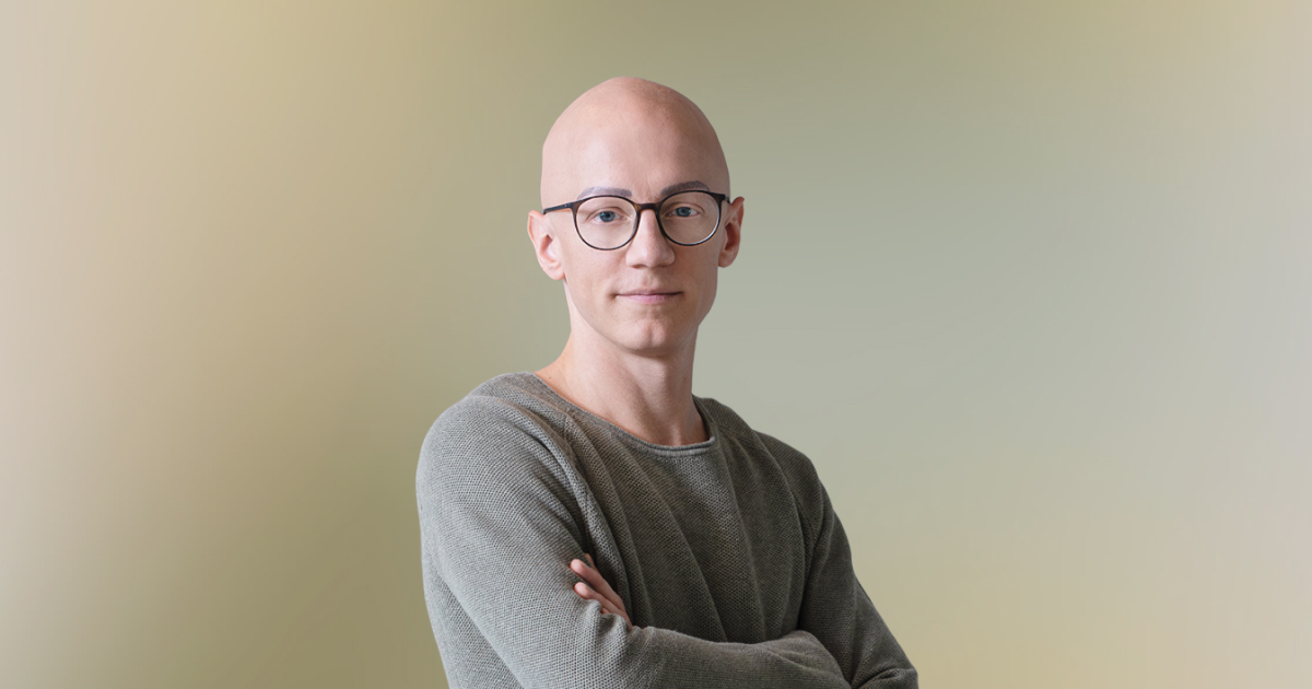 Portr&auml;t einer Person im beruflichen Umfeld mit l&auml;ssiger Kleidung und selbstbewusstem Ausdruck.